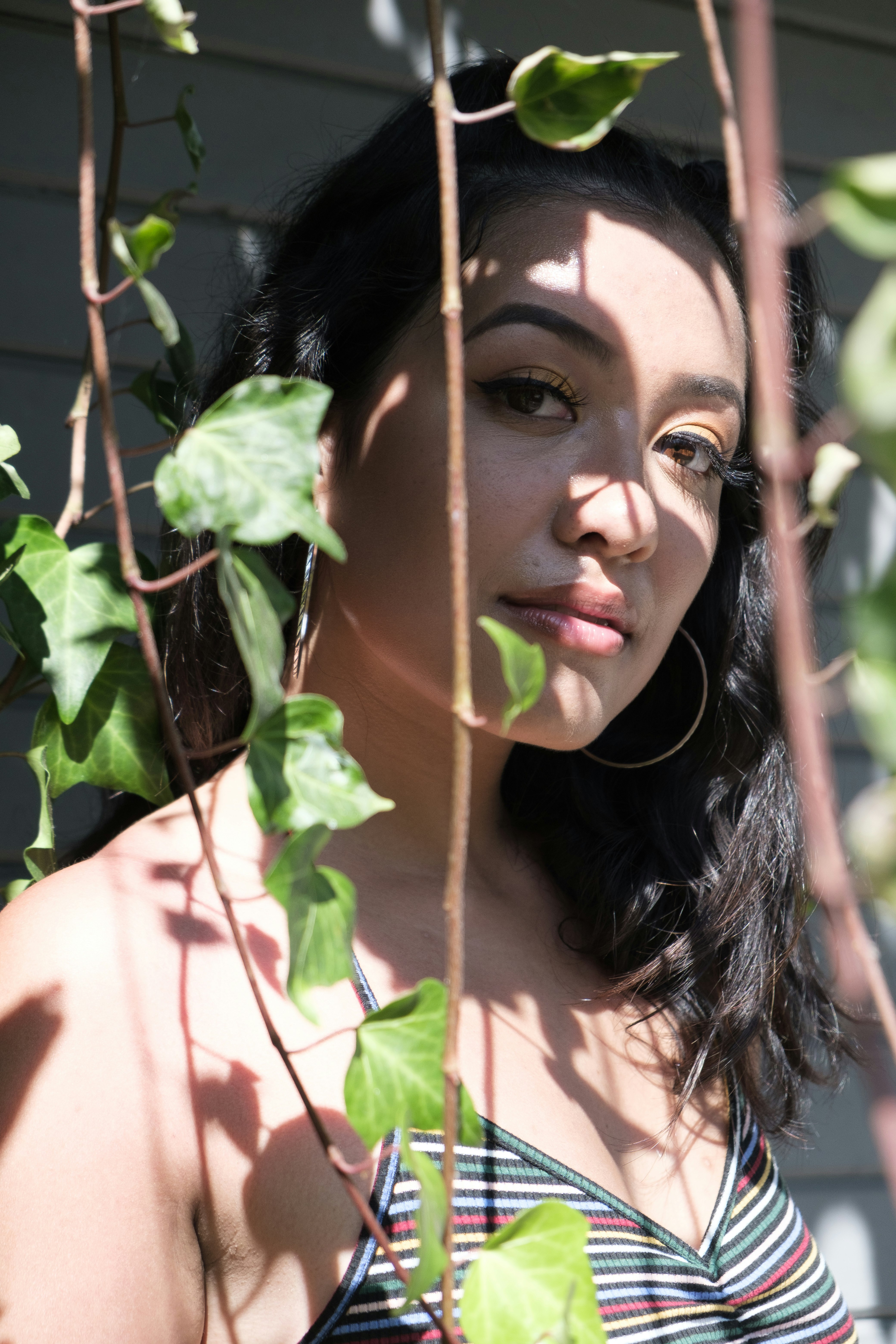 woman in white tank top standing beside green plant during daytime